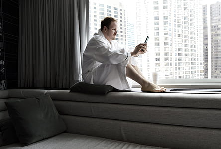 man holding phone while sitting on sofa thumbnail
