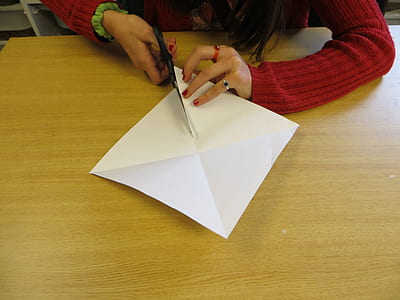 person cutting white printer paper on table thumbnail