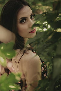 shallow focus photography of woman standing near plants thumbnail