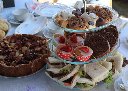 assorted-flavor cupcakes and sandwiches on 3-layer cupcake holder at daytime thumbnail