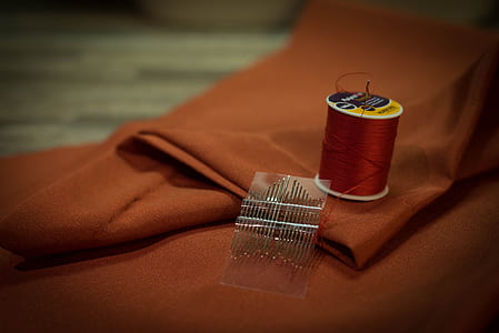thread spool beside needles on textile thumbnail