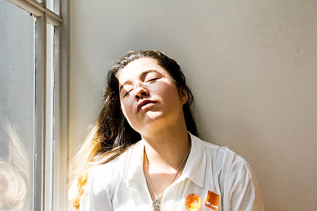 woman leaning on wall with closed eyes during daytime thumbnail