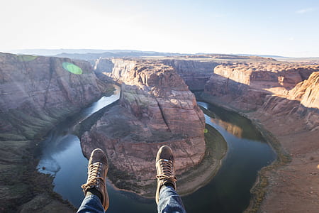 person sitting on mountain cliff near river thumbnail