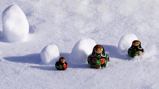 three black-red-and-green Russian dolls on snow fifeld thumbnail