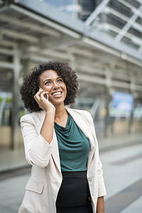 Smiling Woman Holding Phone Standing Beside Building thumbnail