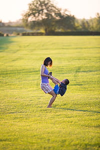 woman playing with boy on grass field thumbnail