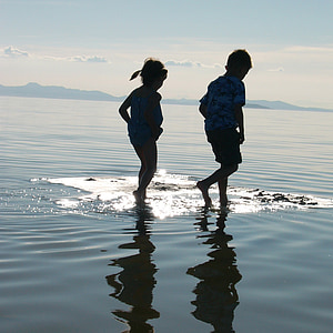 boy and girl walking on the water during daytime thumbnail