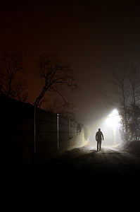 silhouette photography of man walking beside wall near street igh thumbnail