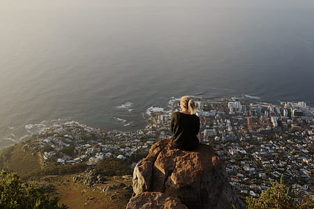 woman sitting on rock facing on city thumbnail