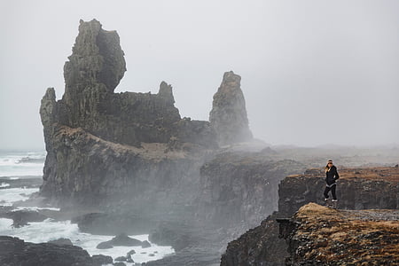 woman in black jacket standing on cliff beside sea thumbnail