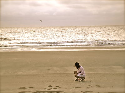 Woman in Pink Cardigan Sitting on Seashore thumbnail