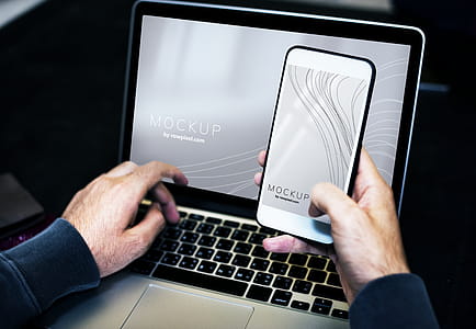 Person Using Smartphone While Facing Laptop Computer thumbnail