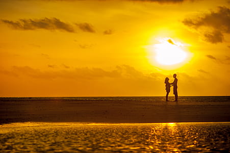 Man and Woman Standing Near Seashore Under Sunset thumbnail