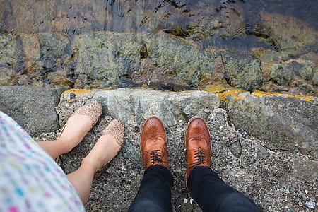 man and woman standing on gray rock hedge near body of water thumbnail