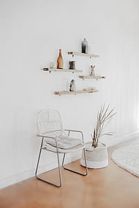 white armchair beside plant under wall shelf thumbnail