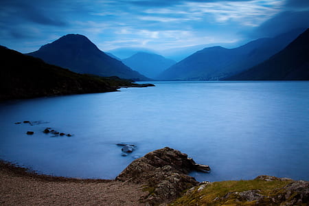 body of water and mountains during cloudy sky thumbnail