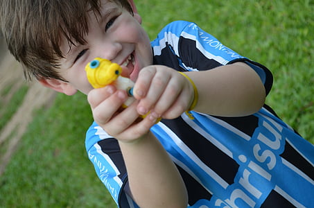 boy playing with yellow plastic water gun during daytime thumbnail