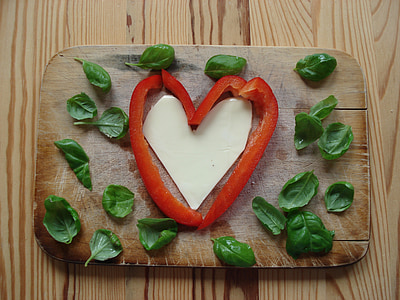 sliced red vegetable form heart and green leafs on brown wooden chopping board thumbnail