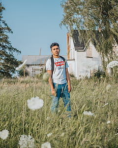 man wearing white Levis crew-neck t-shirt standing on grass during clear blue sky thumbnail