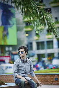 Man Wearing Gray Dress Shirt Sitting on Bench Near Building thumbnail