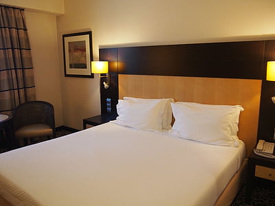 white bedspread beside chair and curtain inside the room thumbnail