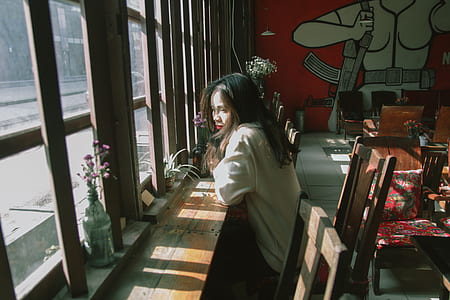 Woman Sitting on Chair Leaning on Table and on Facing Window thumbnail