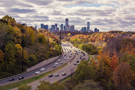 aerial view of vehicles on pave road with cityscape in the background thumbnail