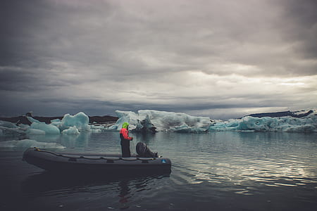 person standing on boat near ice bergs thumbnail