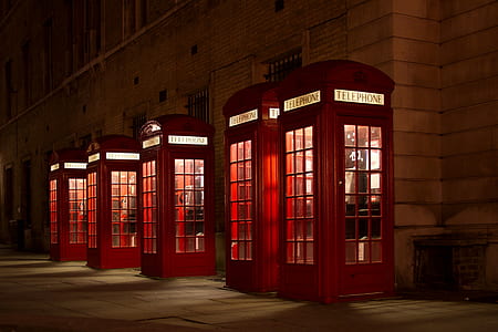 photo of five turned on red telephone booths during nighttime thumbnail