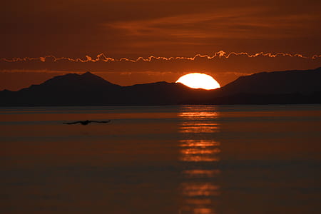 silhouette of mountain near body of water during sunset thumbnail