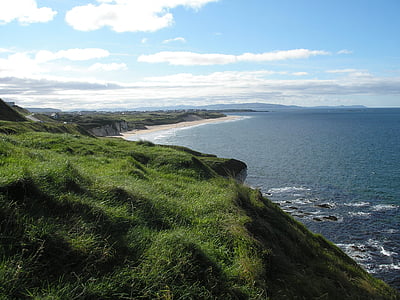green hill and sea water under blue sky thumbnail