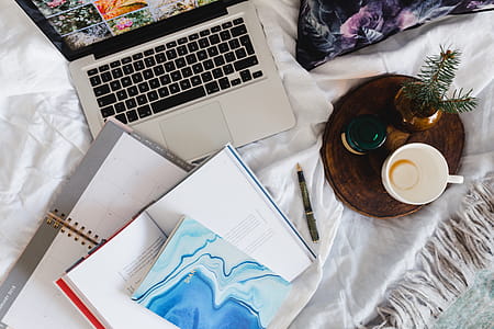 Bed full of pillows and notebooks with Apple gadgets thumbnail