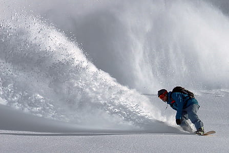 man wearing green jacket snowboarding with avalanche on background thumbnail