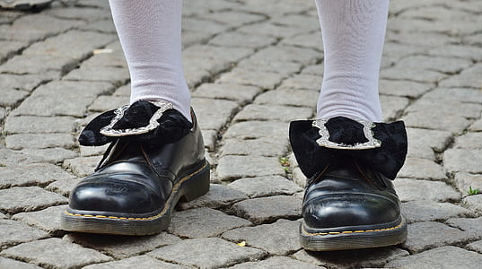 person wearing pair of black leather dress shoes standing on pavement thumbnail