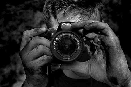 grayscale photography of man capturing Canon DSLR camera thumbnail