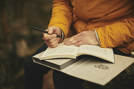 person holding pen and book thumbnail
