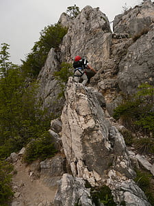 man climbing on gray rock formation during daytime thumbnail