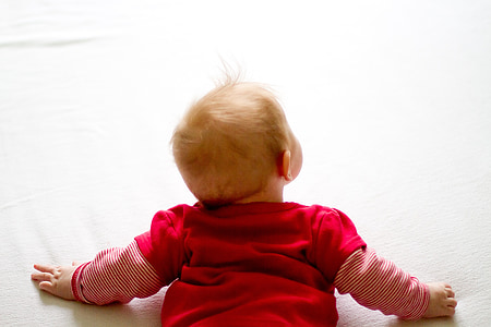 baby wearing red long-sleeved shirt laying on white surface thumbnail