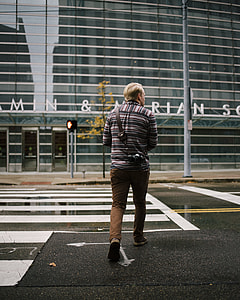 man walking on road beside building thumbnail