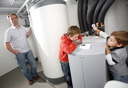 two boys standing between white water heater tank thumbnail