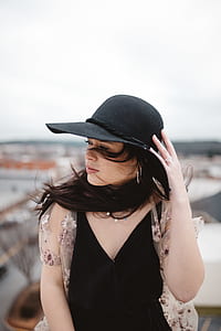 woman wearing black V-neck sleeveless blouse near white wall during daytime thumbnail