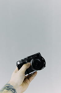 person holding black mirrorless camera thumbnail
