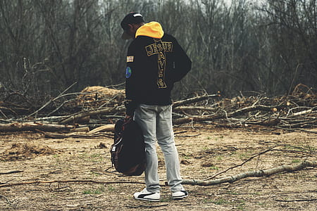 man in black jacket carrying bag outdoors thumbnail