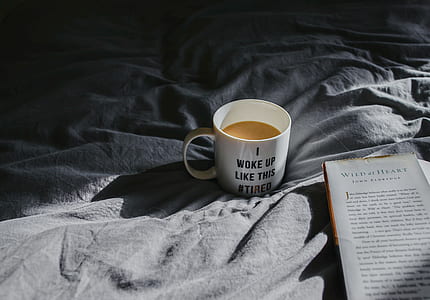 white mug filled with coffee beside book thumbnail