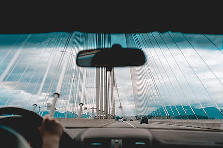 person driving car at metal suspension bridge during daytime thumbnail