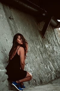 woman in black spaghetti strap dress sitting under bridge thumbnail