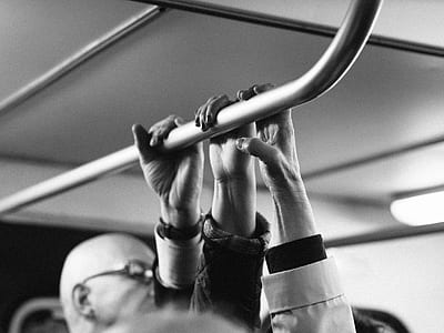 grayscale photo of three person holding on metal bar thumbnail