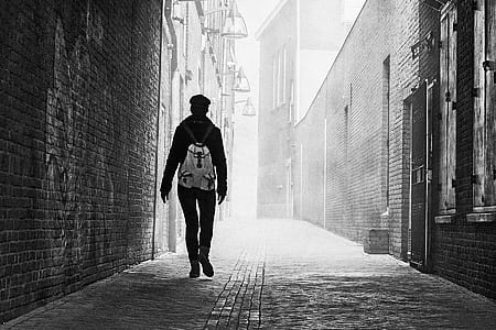 Grayscale Photo of Person Near Brick Wall thumbnail