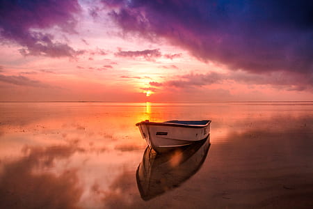 white and brown wooden boat on sea under gray clouds during sunset thumbnail