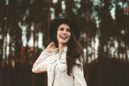 woman wearing black hat and denim jacket laughing thumbnail